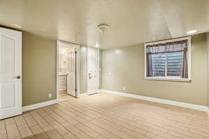 Unfurnished bedroom featuring wood tiled floors, recessed lighting, a textured ceiling, and ensuite bath
