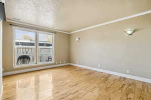 Spare room with crown molding, a textured ceiling, and light wood-style flooring