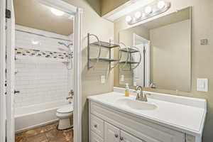 Bathroom with vanity, shower / tub combination, and stone tile floors