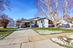 View of front of house featuring driveway, a front yard, and an attached carport
