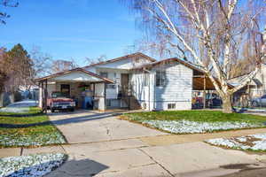 View of front facade featuring driveway, a carport, and a front lawn