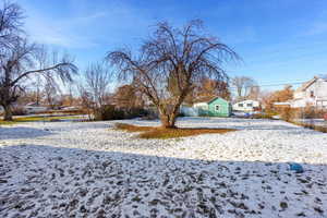 Yard layered in snow with volleyball court and a residential view