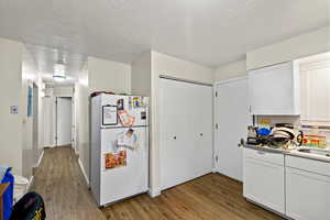 Kitchen with freestanding refrigerator, white cabinets, dark wood-style flooring, and a textured ceiling