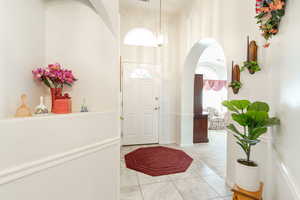 Foyer entrance with arched walkways and light tile patterned flooring
