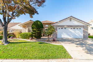 Ranch-style home with brick siding, driveway, and a front yard