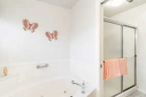 Bathroom with a tub with jets and a stall shower