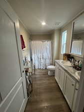 Master bathroom featuring dark wood-type flooring, double vanity, crown molding, a shower with shower curtain, and recessed lighting