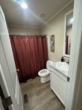 Full bath with curtained shower, vanity, dark wood-style floors, and ornamental molding