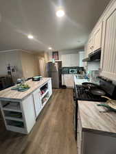Kitchen featuring open shelves, gas stove, white cabinets, freestanding refrigerator, and recessed lighting
