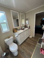 Master bathroom featuring dark wood-type flooring, double vanity, connected bathroom, and crown molding