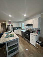 Kitchen with stainless steel appliances, white cabinets, open shelves, a center island, and dark wood-style floors