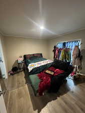 Master bedroom with wood finished floors, ornamental molding, and a decorative wall
