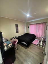 Bedroom featuring ornamental molding, hardwood / wood-style floors, a decorative wall, and a desk