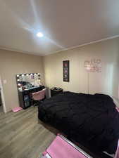 Bedroom featuring an office area, wood finished floors, and crown molding