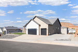 View of front of house with a garage, concrete driveway, board and batten siding, and stone siding
