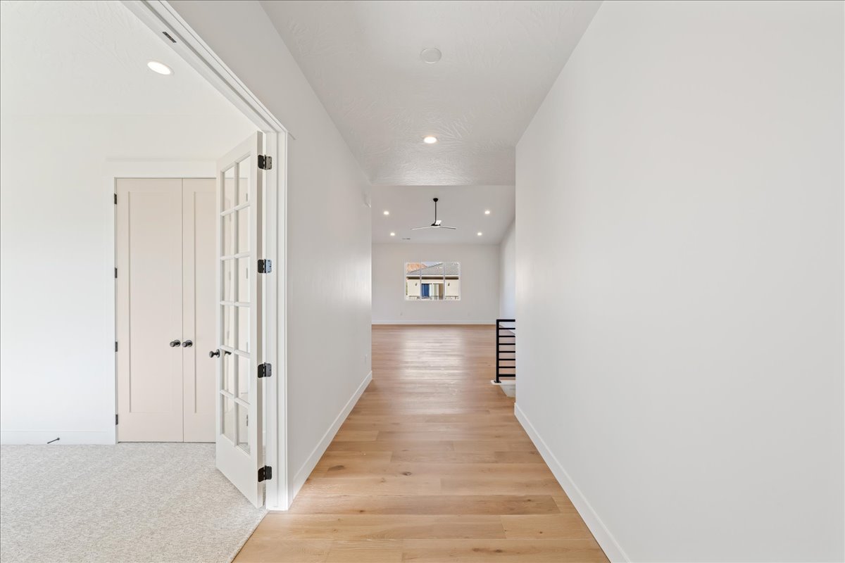 Hall with light wood finished floors and recessed lighting