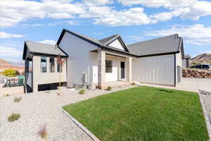 View of front facade with a front yard, board and batten siding, and a porch
