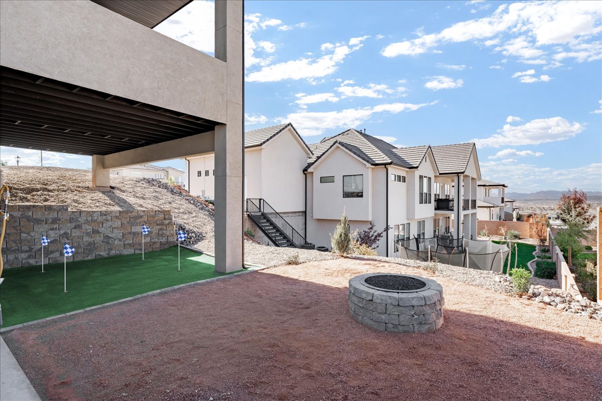 View of patio / terrace featuring an area to practice putting, a fire pit, stairs, and a residential view