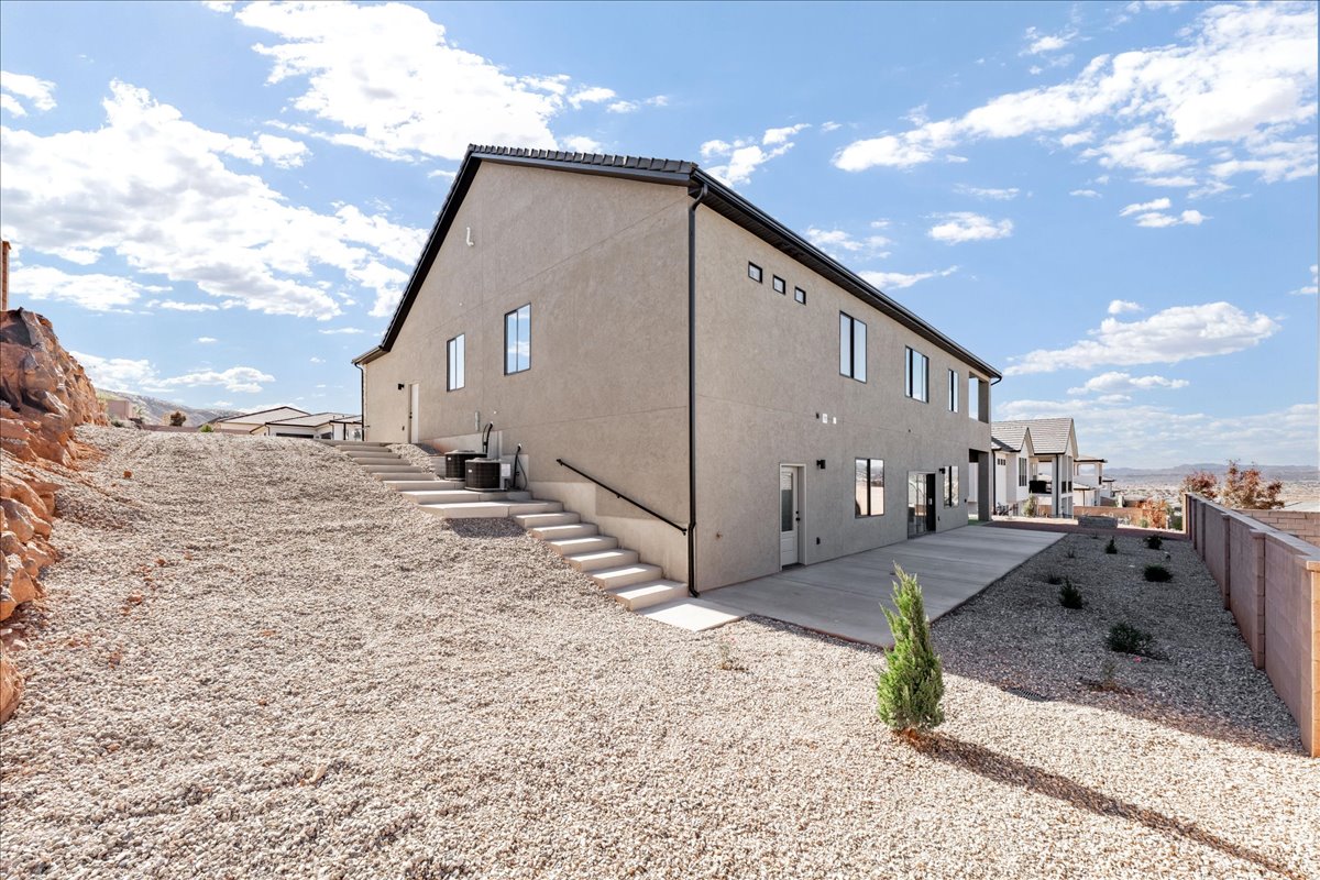 View of side of home featuring stucco siding, stairs, and a fenced backyard