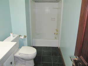 Bathroom featuring vanity, dark tile patterned flooring, and shower / washtub combination
