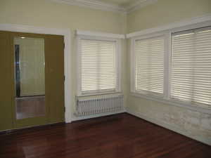 Bedroom with radiator, dark wood-type flooring, and crown molding