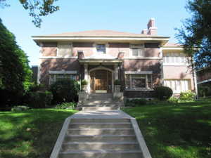 View of front of property featuring a chimney, a front yard, and brick siding
