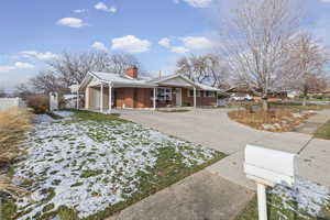 View of home's exterior with concrete driveway, a porch, a chimney, an attached carport, and brick siding