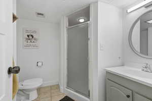 Bathroom featuring vanity, light tile patterned flooring, and a stall shower