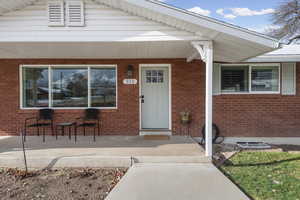Property entrance featuring covered porch and brick siding