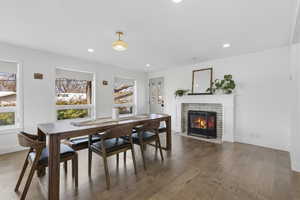 Dining room featuring a brick fireplace, hardwood / wood-style flooring, ornamental molding, and recessed lighting