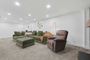 Carpeted living area featuring recessed lighting and a textured ceiling