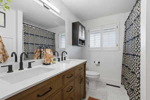 Full bathroom featuring light tile patterned floors, double vanity, and curtained shower