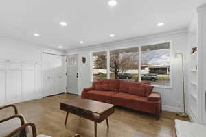 Living room with light wood-type flooring, crown molding, and recessed lighting