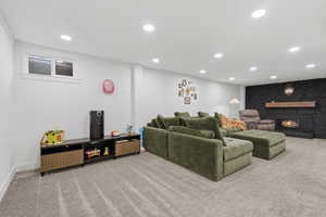 Living room with light carpet, a stone fireplace, and recessed lighting