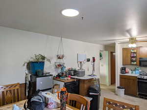 Kitchen featuring black appliances, light countertops, a ceiling fan, and brown cabinets