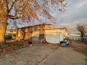 View of front of home with concrete driveway, a garage, and extra parking