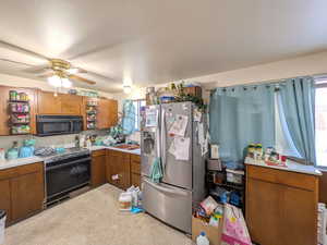 Kitchen featuring brown cabinets, black appliances, light countertops, ceiling fan, and light carpet