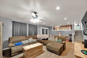 Living room with stairway, recessed lighting, a ceiling fan, wood finished floors, and a textured ceiling