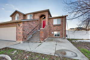 View of front of home featuring brick siding, a patio, and driveway