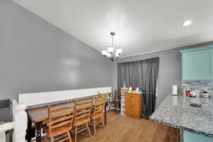 Dining area with light wood-style flooring, a chandelier, vaulted ceiling, and recessed lighting
