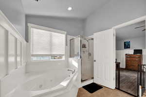 Bathroom featuring a tub with jets, a shower stall, light tile patterned floors, vaulted ceiling, and recessed lighting