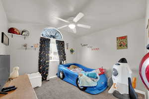 Bedroom with carpet floors, ceiling fan, and vaulted ceiling