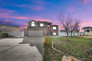 View of front facade featuring brick siding, concrete driveway, and an attached garage