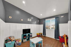 Rec room with a wainscoted wall, a decorative wall, dark wood-style floors, and recessed lighting