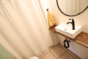 Full bathroom with light tile patterned floors and curtained shower