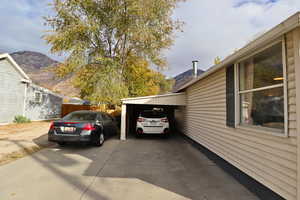 View of side of home with driveway, a mountain view, and a carport