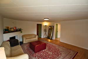 Living area with a fireplace, crown molding, a paneled ceiling, and wood finished floors