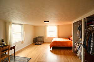 Bedroom featuring a textured ceiling, light wood finished floors, and a closet