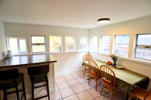 Dining area with a decorative wall, plenty of natural light, and light tile patterned floors