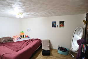 Bedroom featuring wood finished floors and a textured ceiling